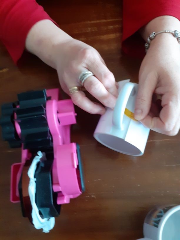 Retrait du transfert sur un mug fraîchement pressé, avec les moules colorés de l'atelier